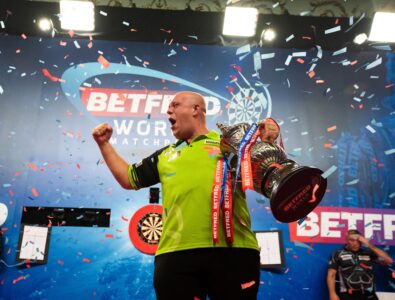 Michael van Gerwen celebrating on stage while holding the World Matchplay darts trophy in Blackpool.