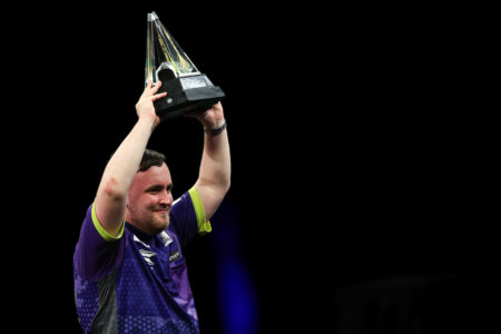 Luke Littler lifts the 2024 BetMGM Premier League Darts trophy.
