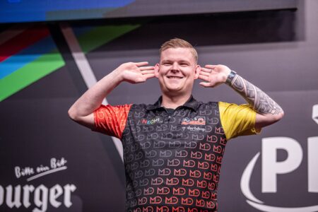 Mike de Decker on stage playing darts