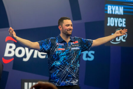 Luke Humphries celebrates on the World Grand Prix stage.