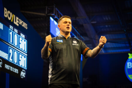 Luke Woodhouse on stage playing darts