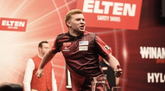 Cam Crabtree on stage playing darts